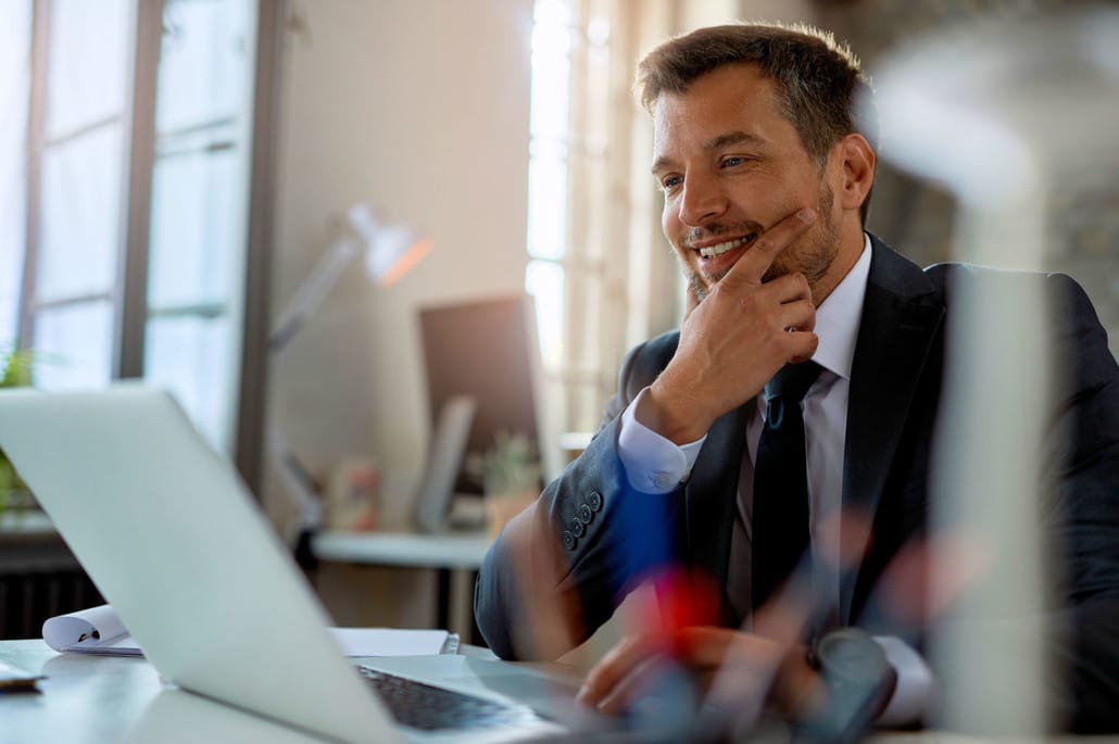 man in a suit looking at a computer smilling